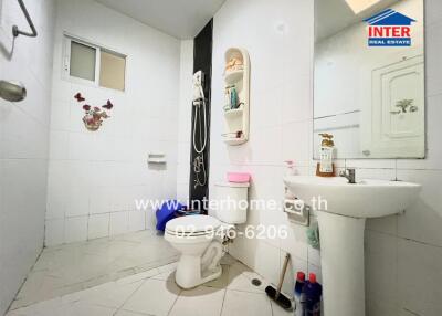 Bright bathroom with white tiles, sink, toilet, and shower