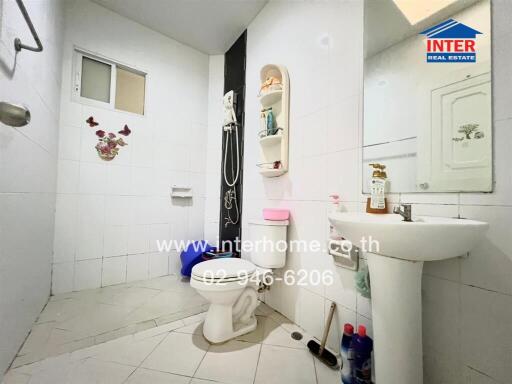 Bright bathroom with white tiles, sink, toilet, and shower