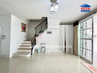 Modern living room with staircase, large window, and hanging light fixtures