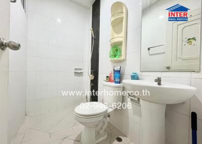 Bathroom with white tiles and fixtures, including a sink, toilet, and shower