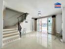 Living room with stairs, large window, and tiled floor