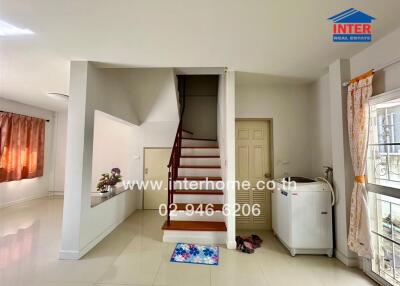 Bright living area with staircase and laundry machine