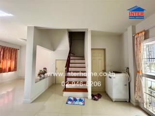 Bright living area with staircase and laundry machine