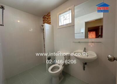 Bathroom with white toilet, sink, and shower area
