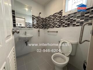 Modern bathroom with black and white tile accent wall, sink, toilet, and shower