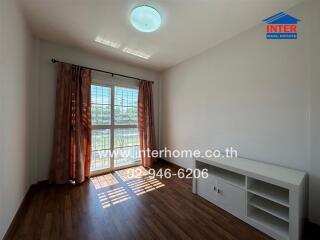 Empty bedroom with wooden floor, window with curtains, and a white shelf