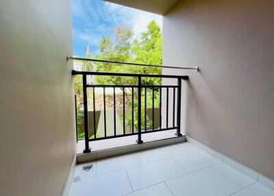 Small, tiled balcony with metal railing and partial outdoor view