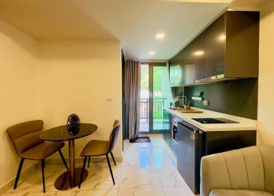 Modern kitchen and dining area with sleek design, featuring a small dining table, chairs, and essential appliances.