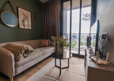 Modern living room with a comfortable sofa, glass-top coffee table, wall art, large windows, and balcony view