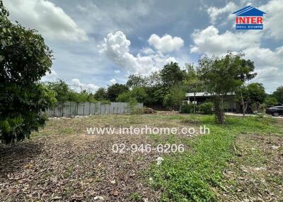 Vacant land with greenery and partial fencing