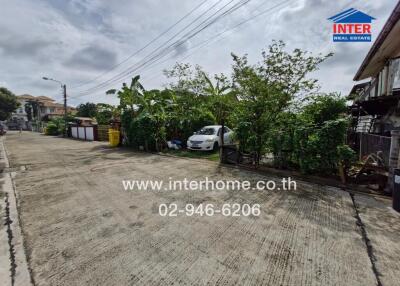 street view of property with greenery and parked car