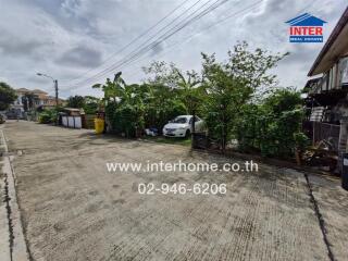 street view of property with greenery and parked car