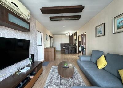 A modern living room with wooden flooring, a gray sofa, coffee table, and dining area.