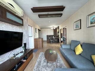 A modern living room with wooden flooring, a gray sofa, coffee table, and dining area.