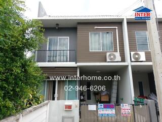 Two-story residential building exterior with balcony and air conditioning units