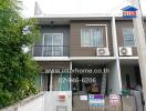 Two-story residential building exterior with balcony and air conditioning units