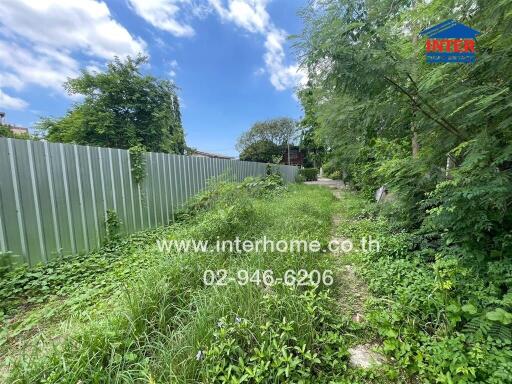 Backyard of a property with overgrown grass and metal fence