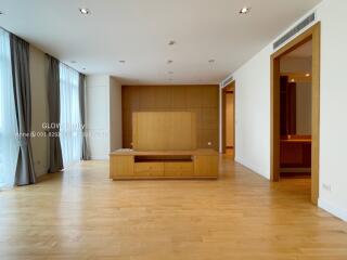 Spacious modern living room with light wood flooring, large windows, and built-in furniture