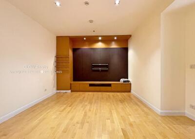 Spacious and well-lit living room with wooden flooring and built-in storage