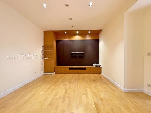 Spacious and well-lit living room with wooden flooring and built-in storage