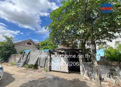 Exterior of a residential property with a tree, fence, and gate