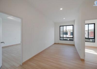 Spacious empty room with large windows and adjacent room visible