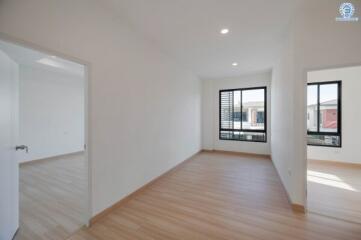 Spacious empty room with large windows and adjacent room visible