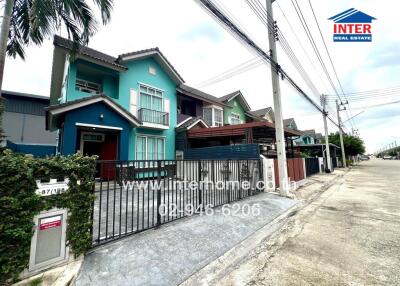 Two-story house with green exterior and fenced yard