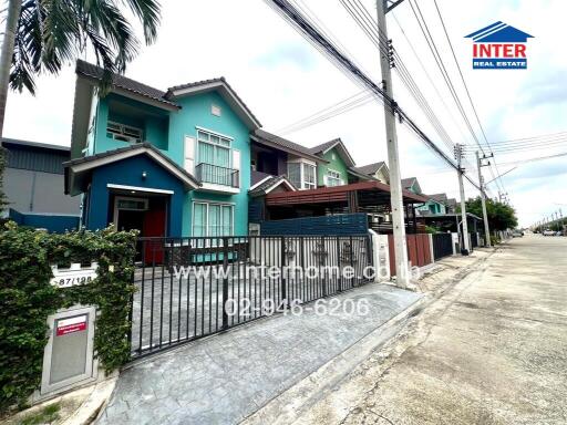 Two-story house with green exterior and fenced yard