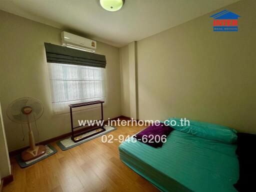 Bedroom with a bed, air conditioner, window with blinds, fan, and a small table.