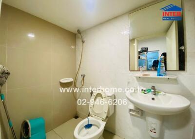 Modern bathroom with white tiles, shower, toilet, and sink