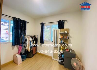 Bedroom with wooden flooring, wardrobe, fan, and personal items
