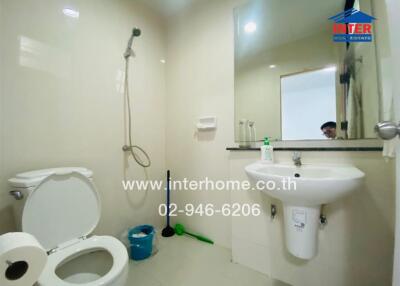 White tiled bathroom with a shower, toilet, and sink.