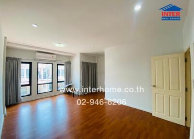 Spacious and well-lit living room with wooden flooring and large windows.