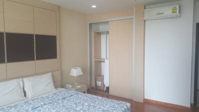 Well-lit bedroom with a bed, nightstand, closet, and air conditioning unit