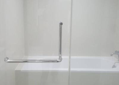 Modern bathroom with bathtub, grab bar, and glass shower door