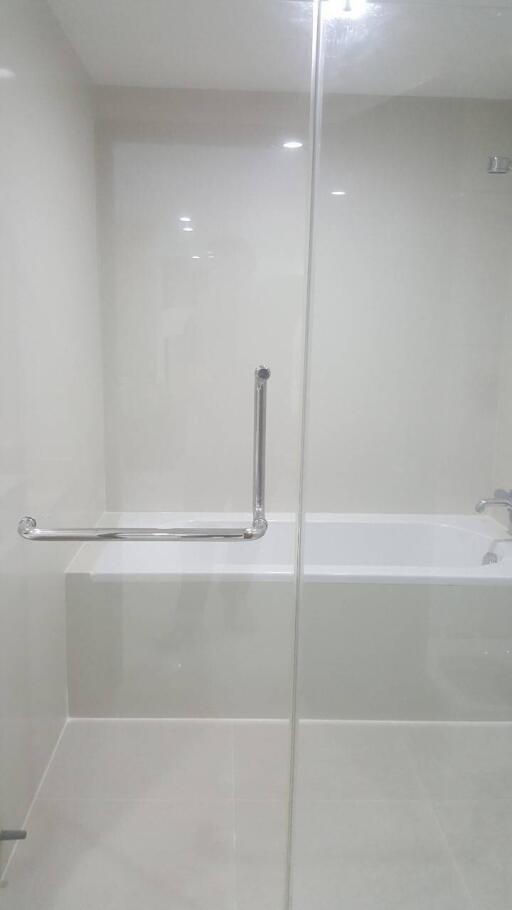 Modern bathroom with bathtub, grab bar, and glass shower door