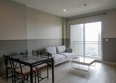 Modern living room with glass table, sofa, and balcony access