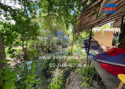 Outdoor area with hammock and shaded seating overlooking a water feature