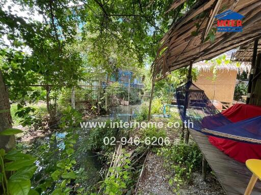 Outdoor area with hammock and shaded seating overlooking a water feature