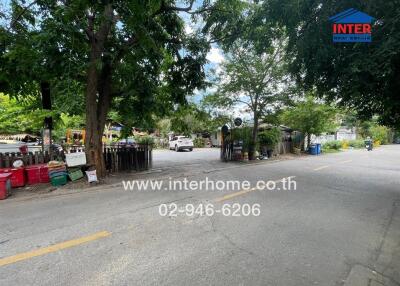 Street view showing the entrance to a property with trees and houses