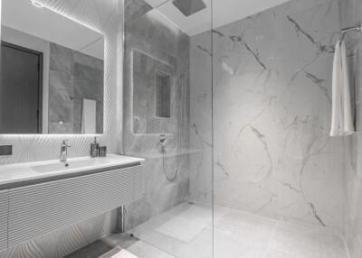Modern bathroom with gray marble tiles, glass shower enclosure, and large mirror