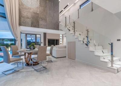Modern living and dining area with glass staircase