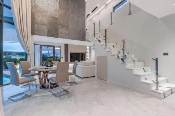 Modern living and dining area with glass staircase