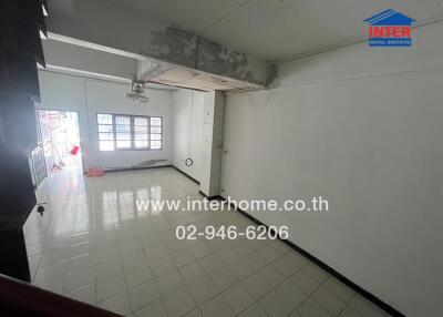 Empty living room with white walls, tiled floor, and ceiling fan