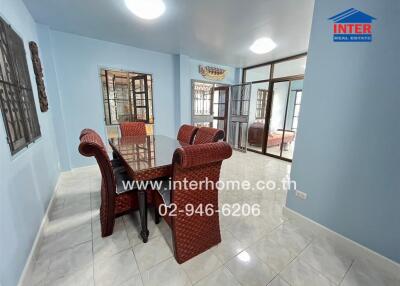 Spacious dining room with a glass-top table and wicker chairs, bright lighting, and tiled flooring