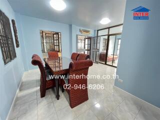 Spacious dining room with a glass-top table and wicker chairs, bright lighting, and tiled flooring