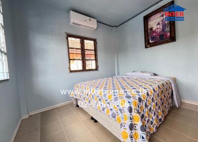 Bedroom with air conditioner, double windows, and patterned bedding