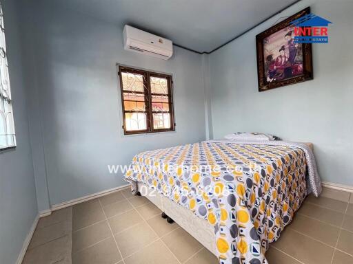 Bedroom with air conditioner, double windows, and patterned bedding