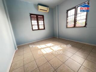 A well-lit bedroom with tiled flooring and air conditioning.